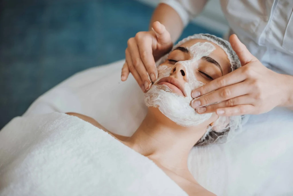 Esthetician applying a facial mask during an extraction treatment.