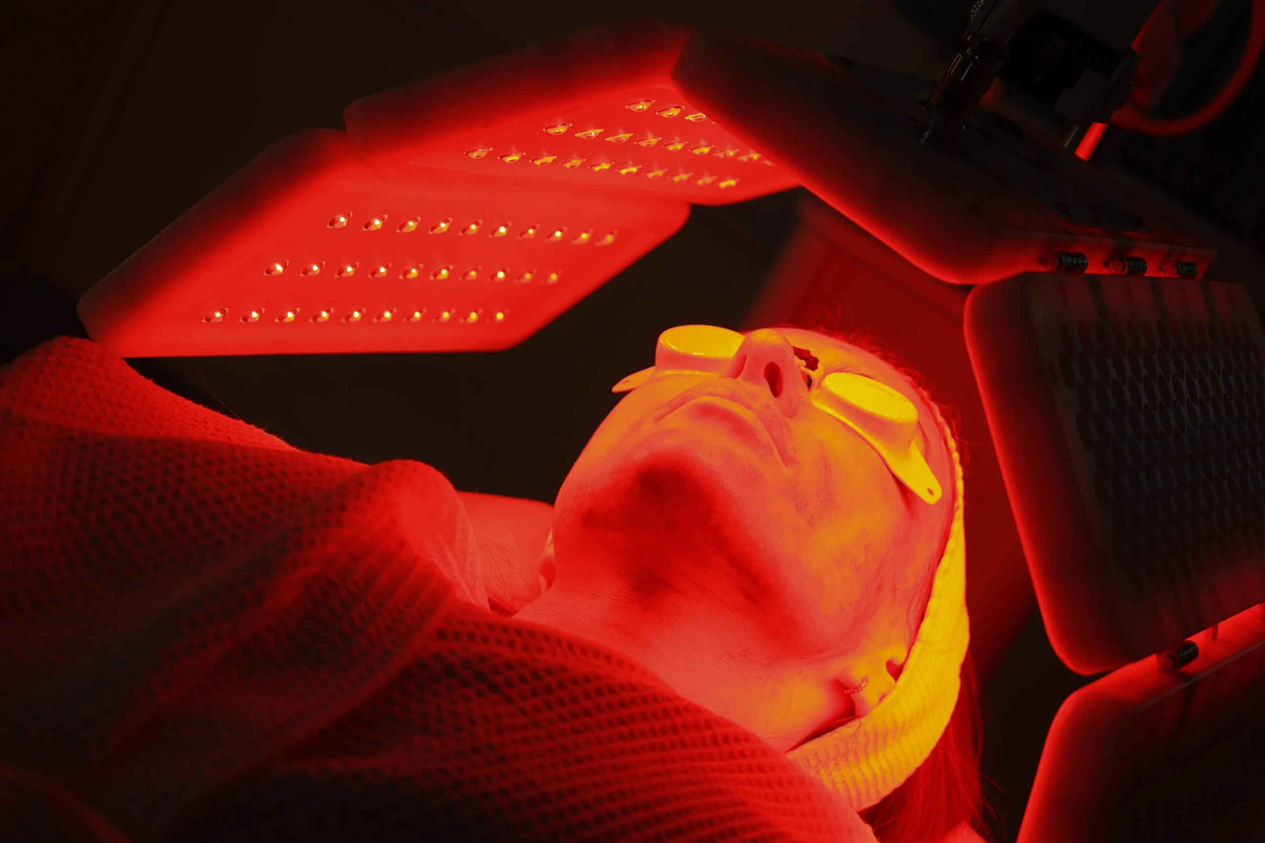 Woman using a red light therapy sauna to improve skin health and appearance.